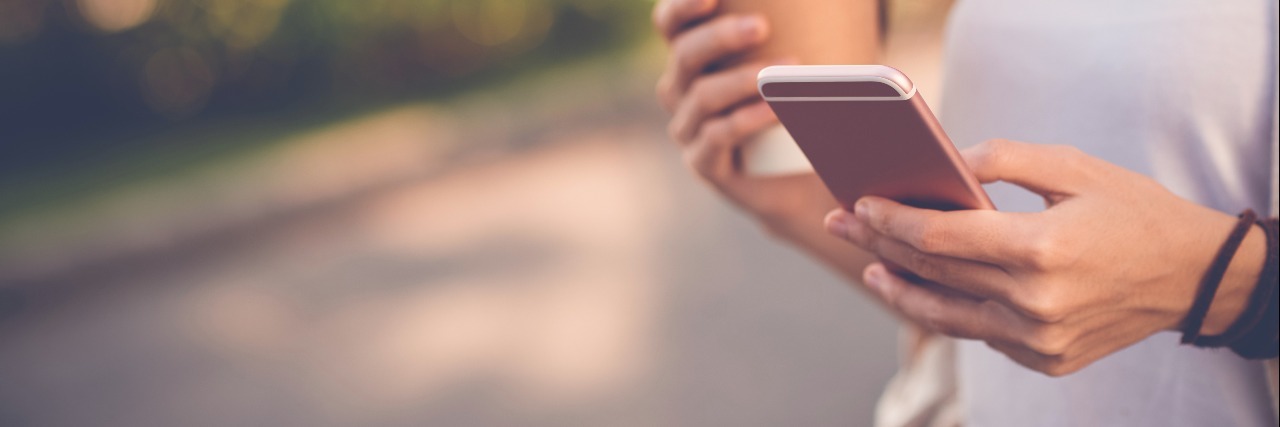 How a Text Message Can Help Someone With Anxiety Close-up image of woman texting and drinking coffee outdoors