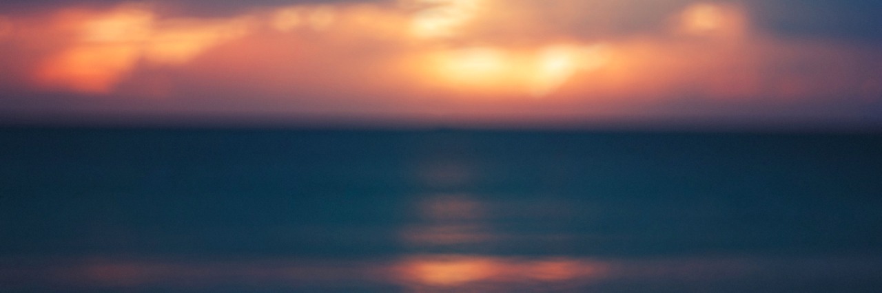 Blurred Image of ocean with sunset and gray clouds