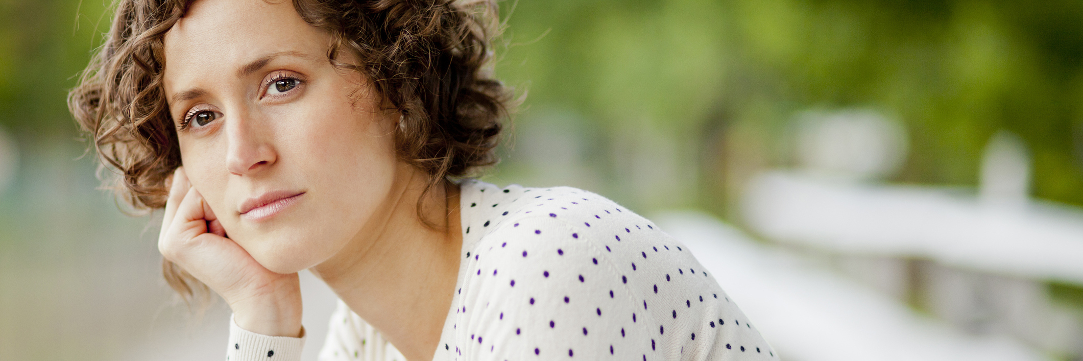 The Mental and Emotional Effects of Living With Ulcerative Colitis woman sitting on a bench looking upset