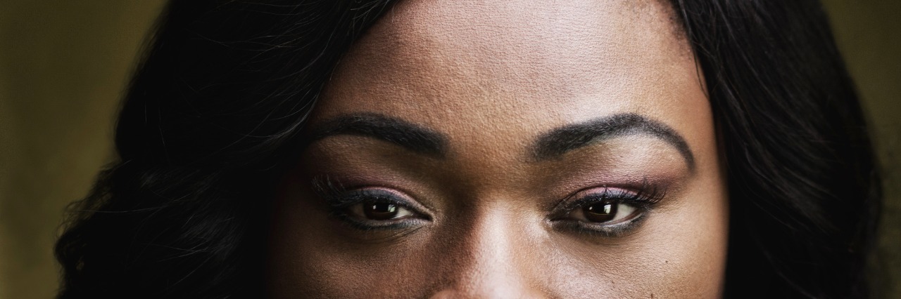 African American woman with a hat obscuring all but her eyes.