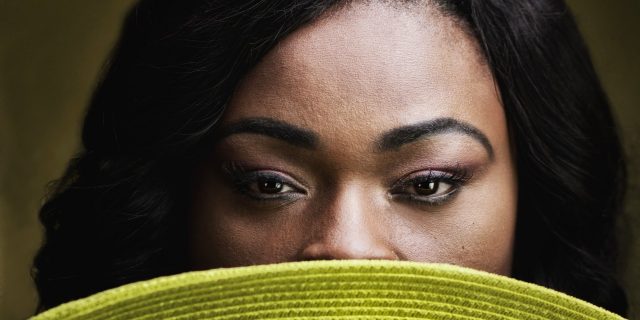 What It Was Like Growing Up With Psoriasis as an African American Woman African American woman with a hat obscuring all but her eyes.