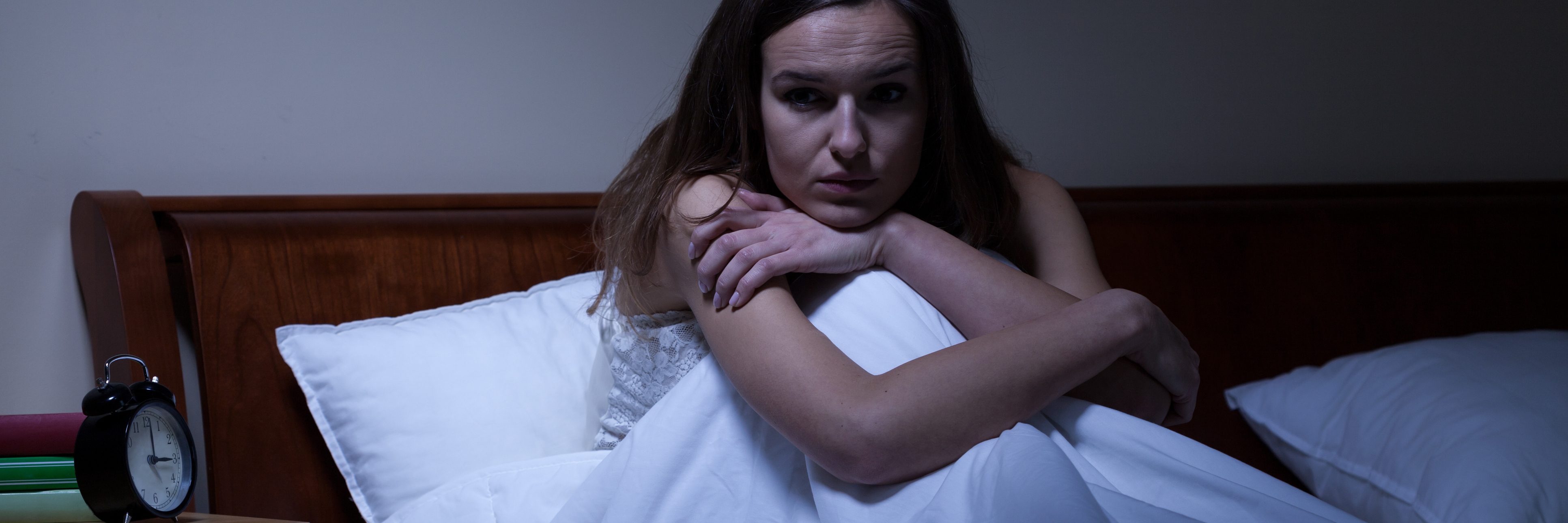 young woman with insomnia or after nightmare sitting up in bed