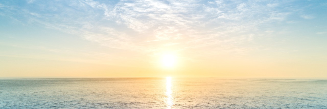 Coping With Multiple Sclerosis Using Phrase 'Grin and Bear It' sunrise with clear blue sky over a calm ocean