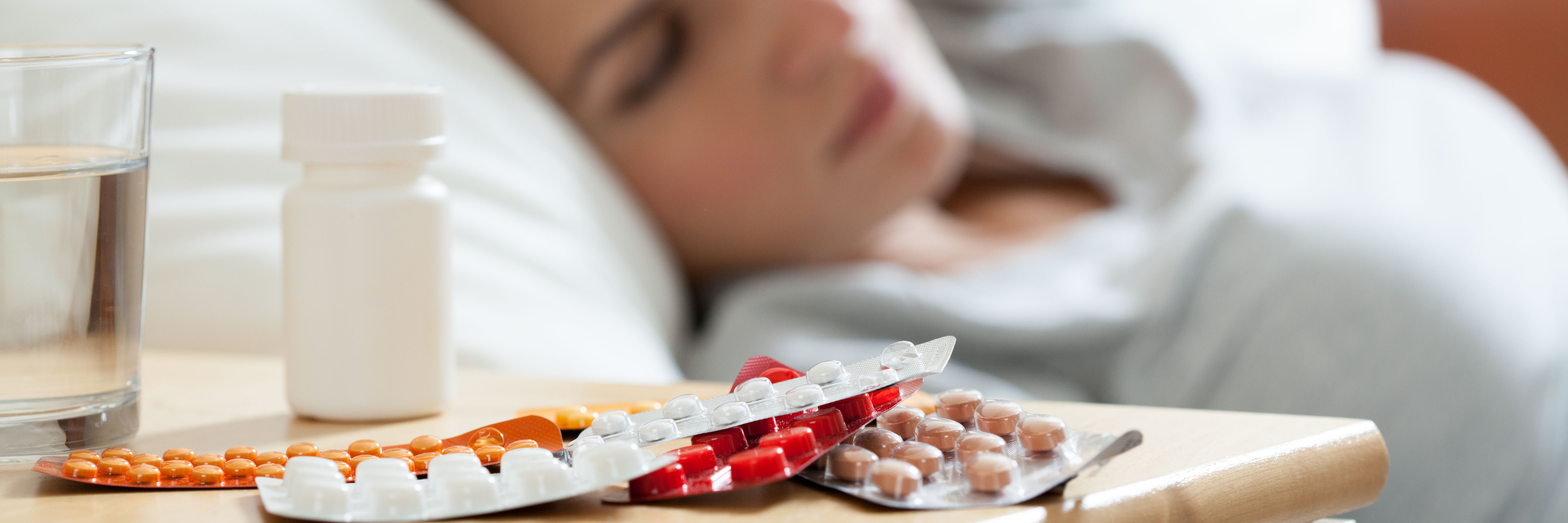 What Happens When I Forget to Take My Antidepressants medication on night table in bedroom beside unwell looking woman