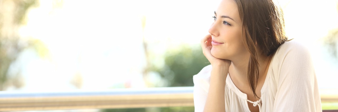 Celebrating Accomplishments With Chronic Illness woman sitting at a table with a cup of coffee and smiling