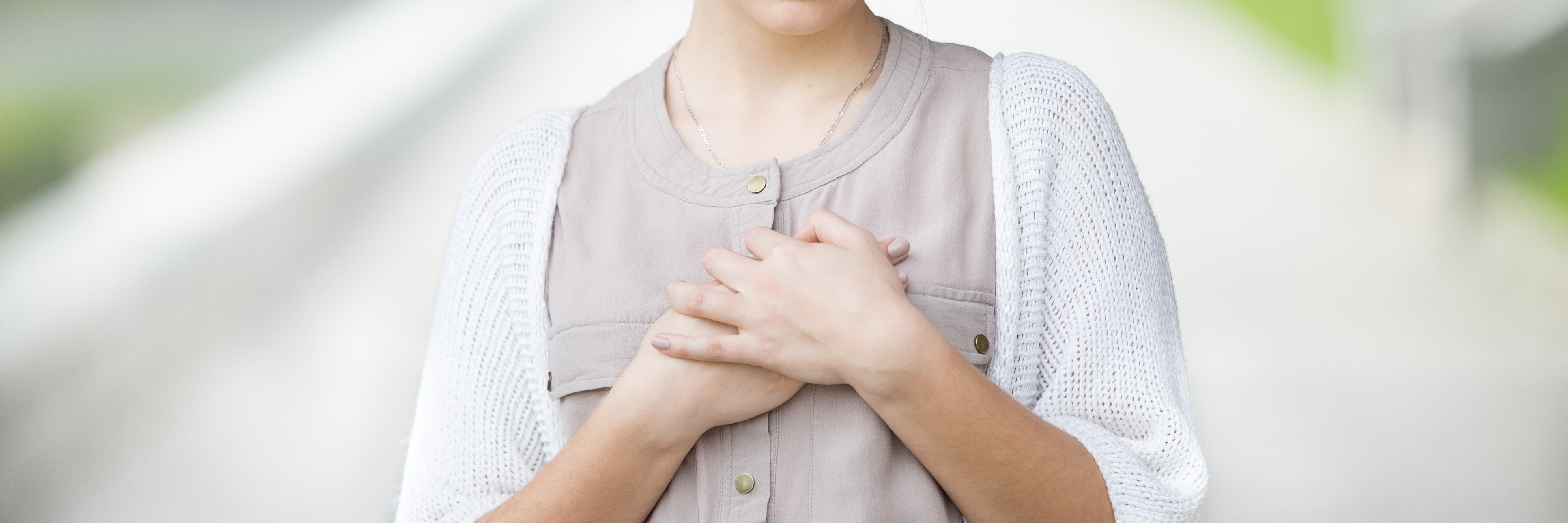 young woman in street holding both hands to her heart or chest