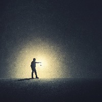 person walking alone in darkness illuminated by a lamp