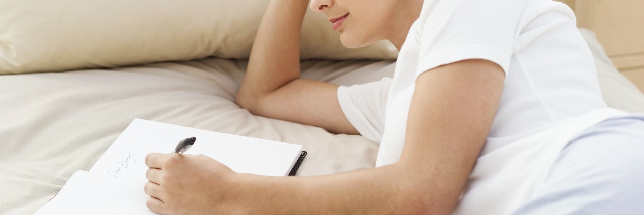 Can Writing Down 3 Things You Did Well Help With Depression? young woman lying on bed writing in notebook