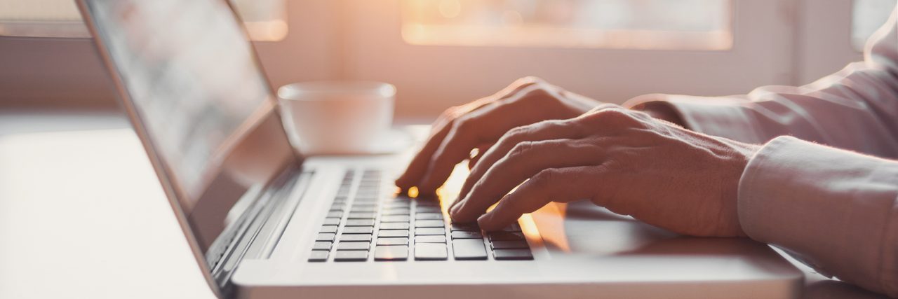 Posting a Green Heart Emoji in Honor of Mental Health Awareness Month Businessman using smart phone and laptop computer