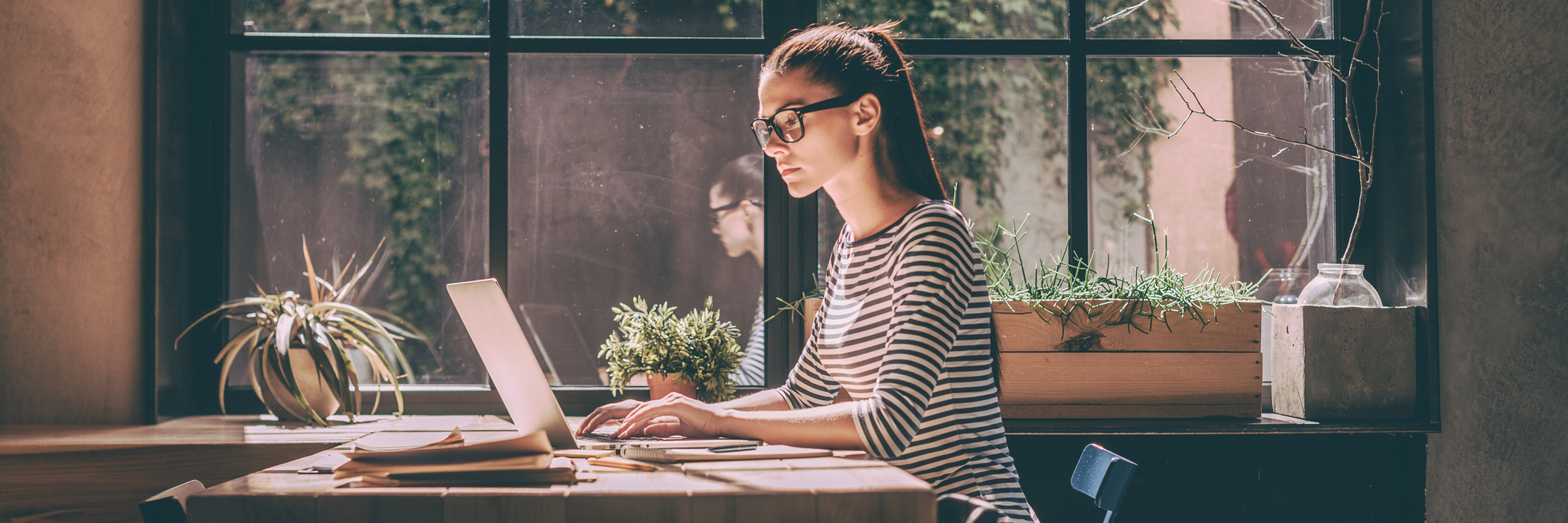 Why My Crashing Computer Reminds Me of My Epilepsy A woman sits by a window, at her computer.