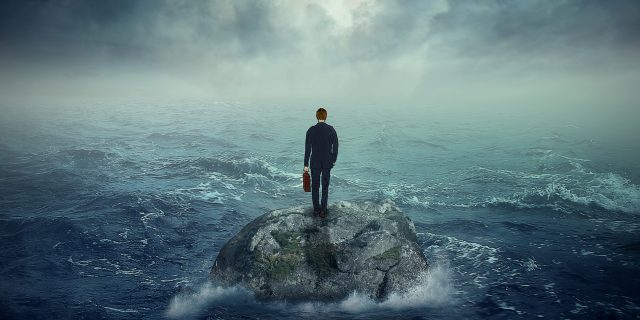 man standing on a rock in the middle of a stormy sea