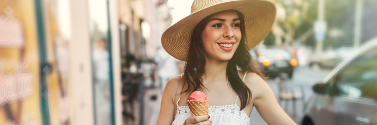 Why We Need to Stop Calling Food 'Good' or 'Bad' A woman walking with her bike holding an ice cream cone
