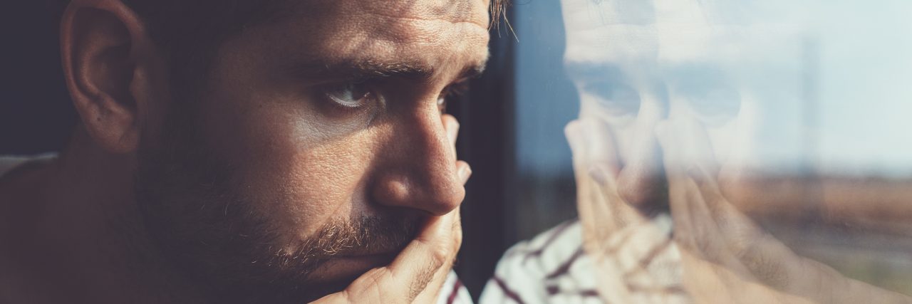 Depression: Why I Don't Recognize Myself in the Mirror sad young man looking at reflection in window
