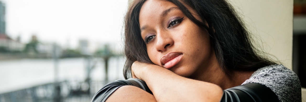 What It Really Means When I Say 'I Am Not Feeling Well' woman looking sad on balcony