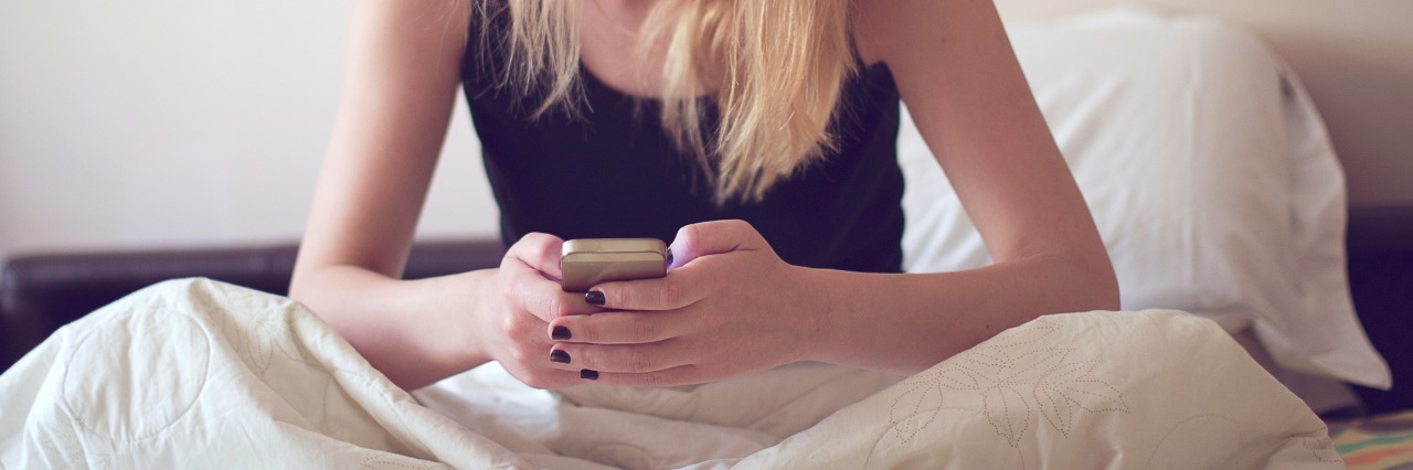 Blonde woman using smart phone in bed