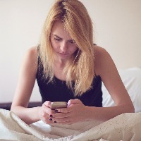 Blonde woman using smart phone in bed