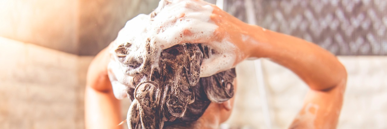 Why Showering Feels Impossible When You Have a Mental Illness Back view of woman washing her hair in the shower.