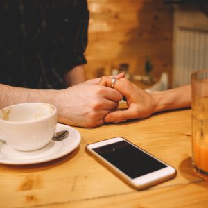 man and woman holding hands in coffee shop