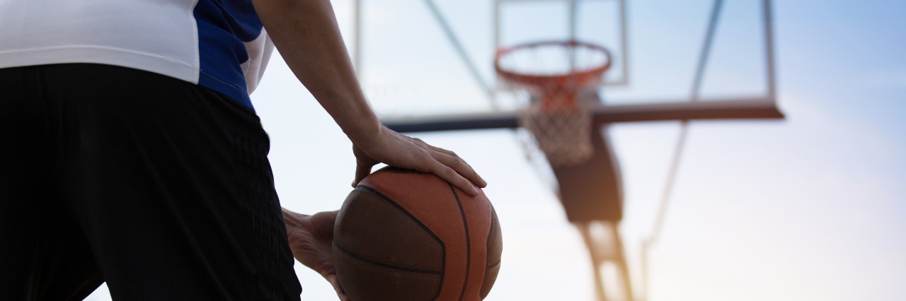 basketball player on court with sun and trees behind net