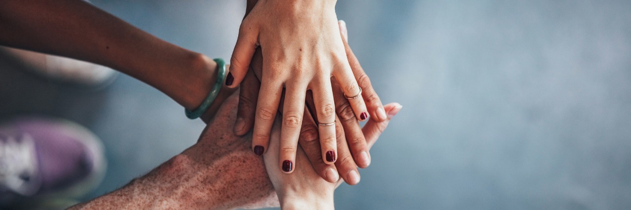 friends putting hands on top of each other for support