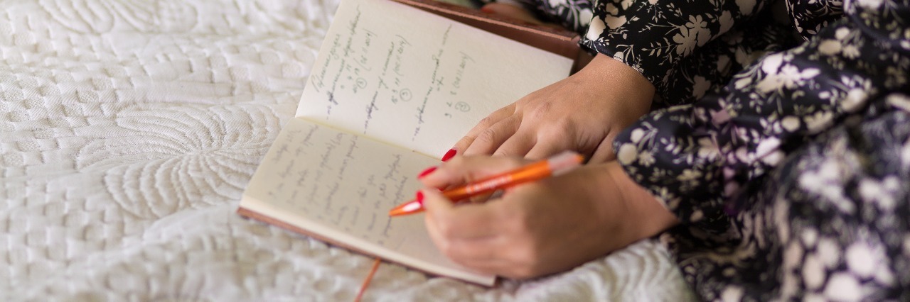 woman writing in journal in bed