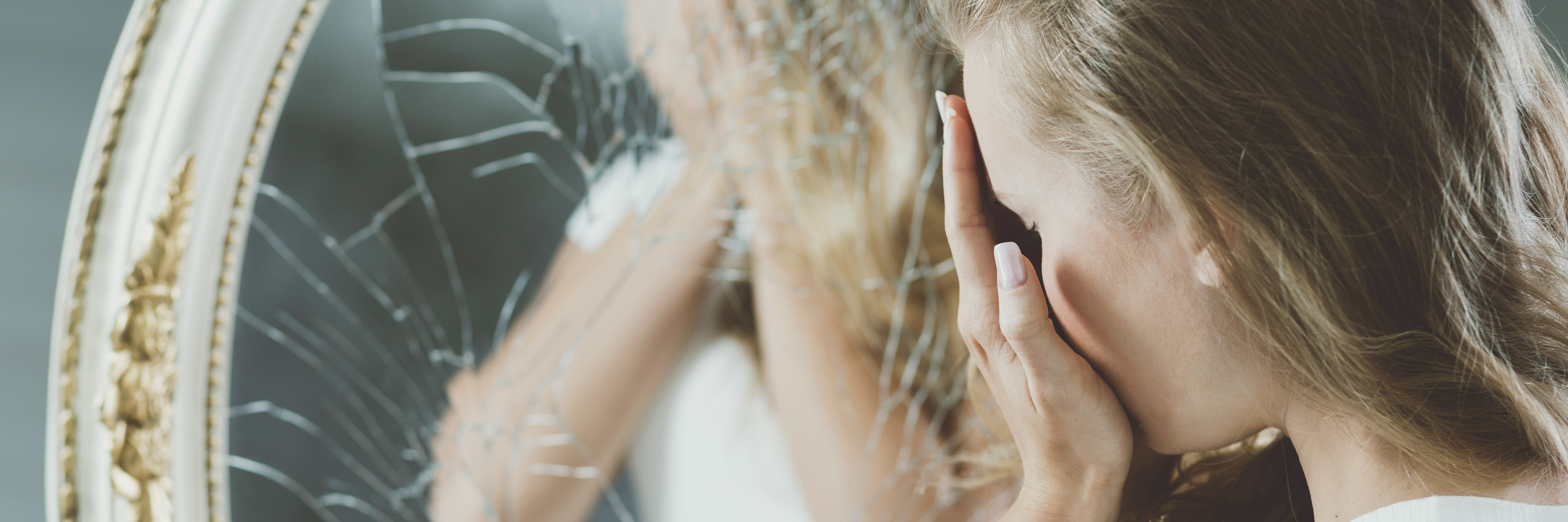 When Self-Doubt Joins My Battle Living With Poor Self-Esteem woman covering her face in mirror with cracks on surface