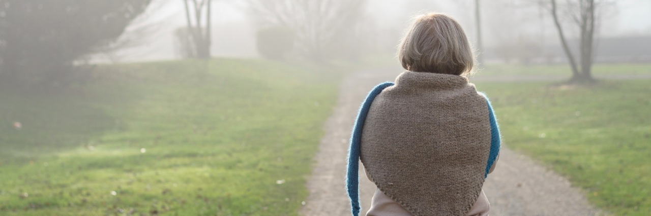 How Anxiety Changed My Retirement Experience Woman in a stylish knitted cape and scarf combination walking along a misty winter road away from the camera in an healthy outdoor active lifestyle concept