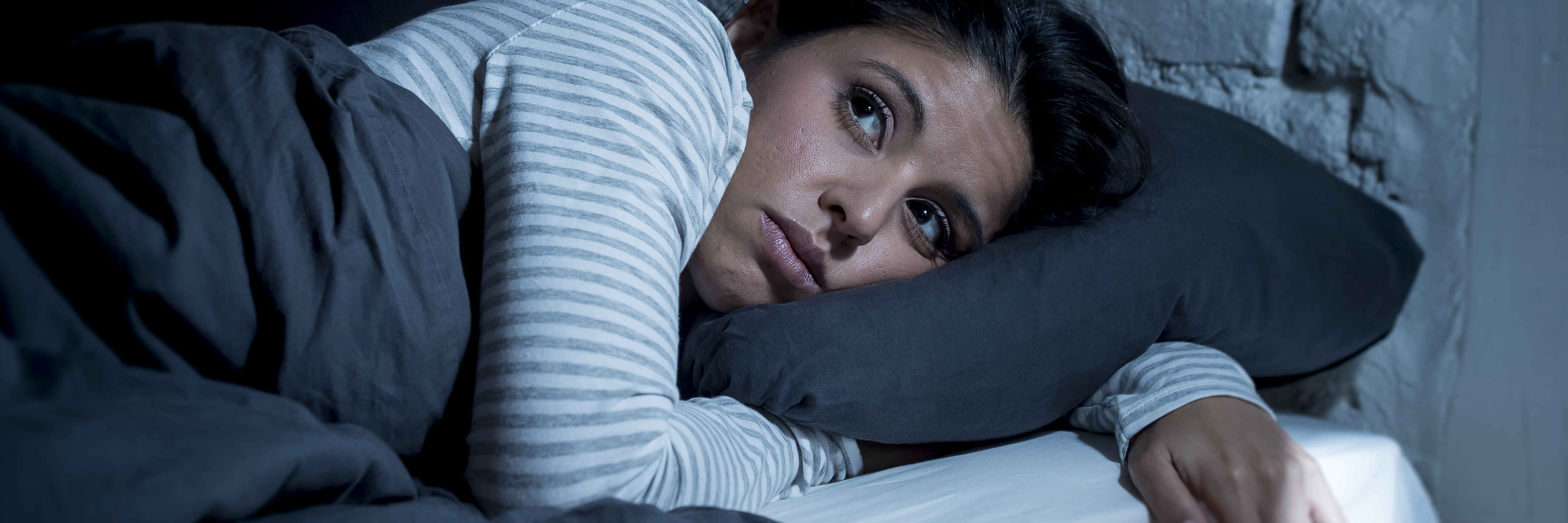 What Happens on My 'Zombie Days' as Someone With Mental Illness young beautiful hispanic woman at home bedroom lying in bed late at night trying to sleep suffering insomnia sleeping disorder or scared on nightmares looking sad worried and stressed