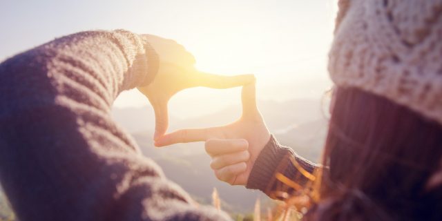 Woman hands making frame gesture with sunrise.