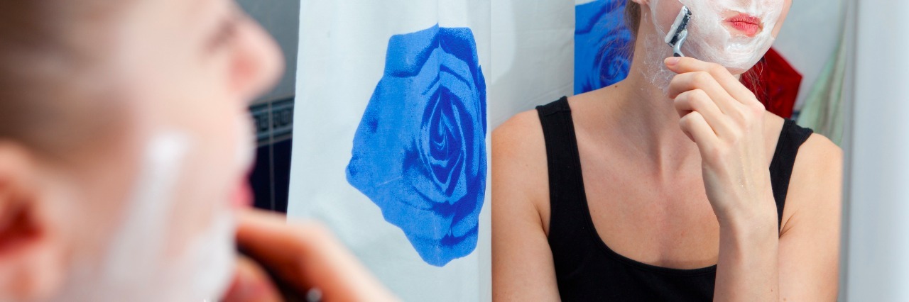 What It's Like Having a Beard as a Woman With PCOS girl shaving face in bathroom mirror
