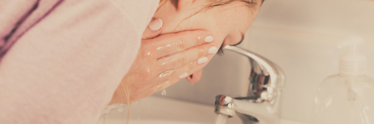 What to Know About Managing Rosacea woman washing her face in the bathroom