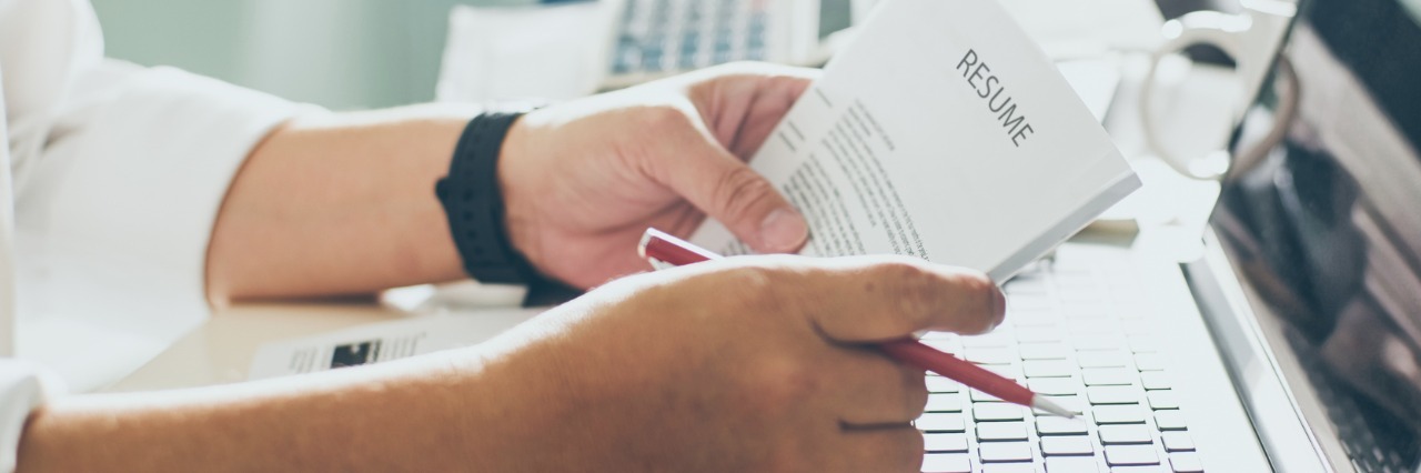 Migraines and Job Hunting — Why Is It So Hard to Find Employment? Man in office holds a resume.