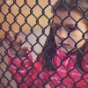young sad, girl looking through a fence
