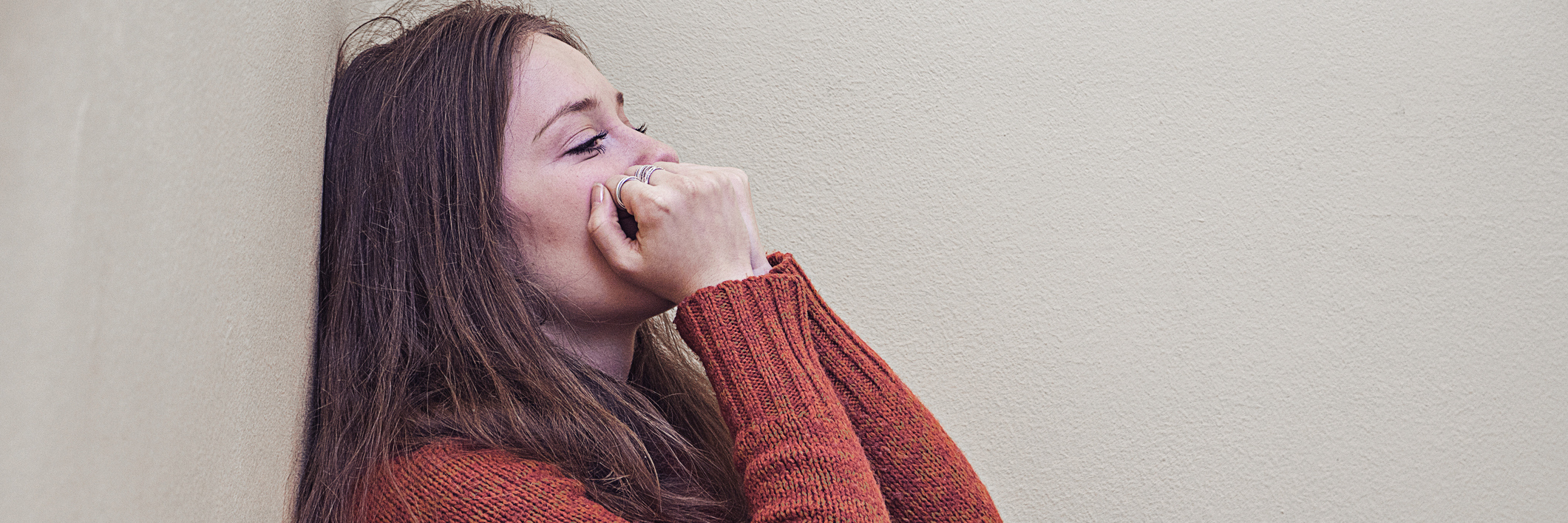 Borderline Personality Disorder and the Self-Critical Narrative woman leaning against wall in despair and sadness with hands to mouth