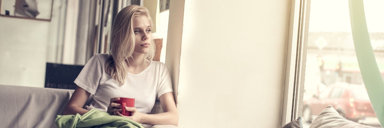 woman holding coffee cup and looking out window