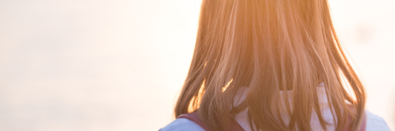 The Reality of Body Dysmorphic Disorder Young woman standing on beach in sea and looking to a sun