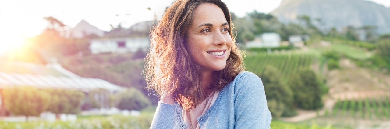 Finding Hope After Diagnosis With Chronic Illness woman standing outside in nature smiling and relaxing