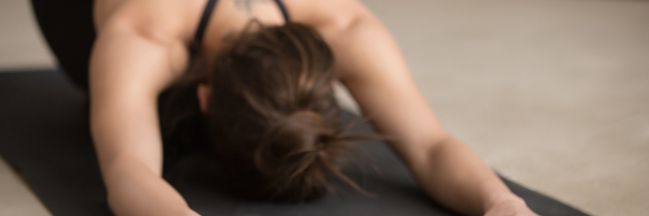 How Hot Yoga Helped Heal Me From My Eating Disorder young woman doing yoga, downward dog position
