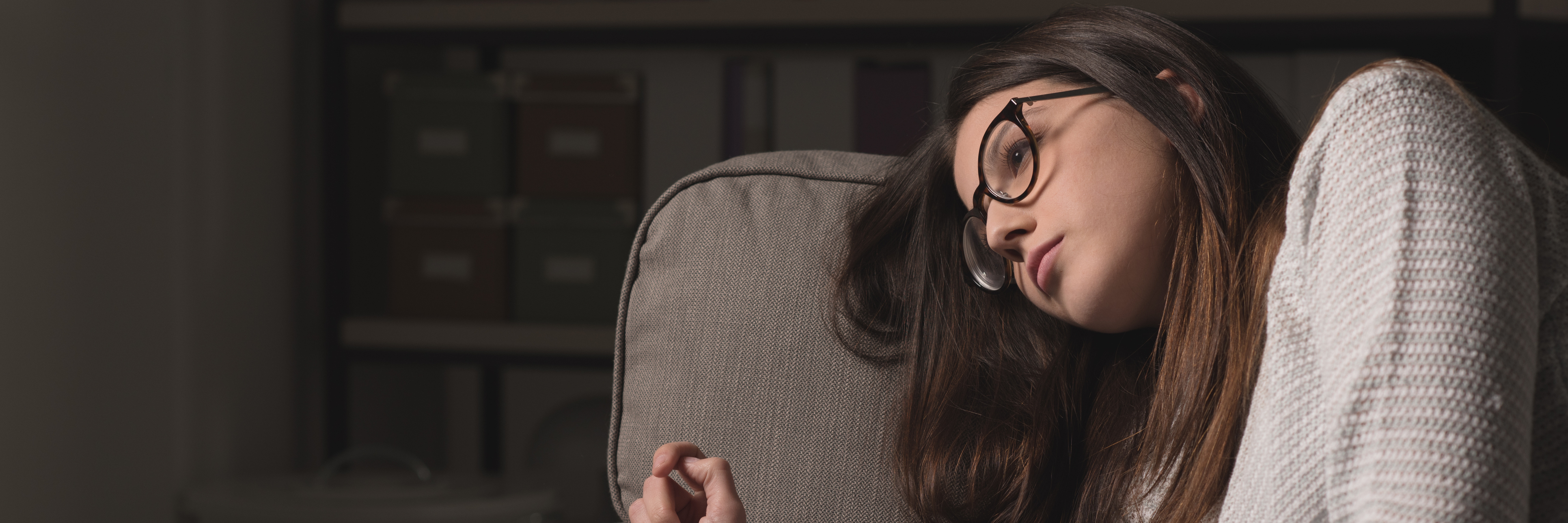 What It's Like to Deal With Depression Exhaustion sad young woman with glasses sitting on couch at home exhausted