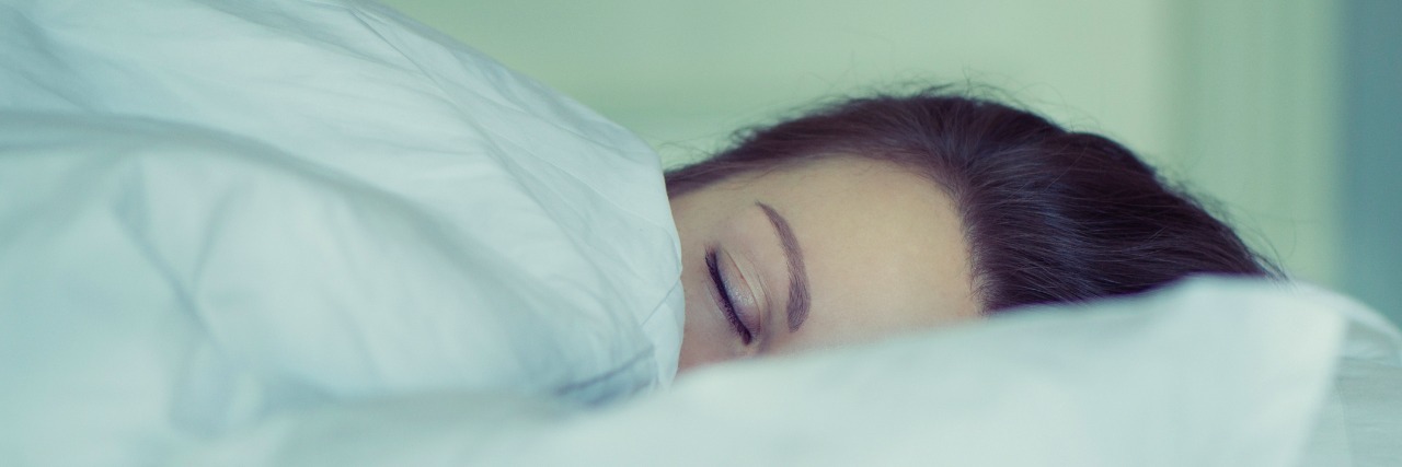 girl in bed with blankets pulled up to eyes