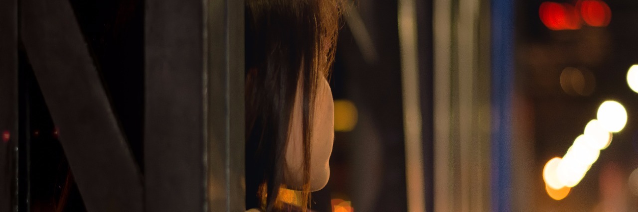 What My Depression and Mania Look Like young woman leaning on bridge with blurred background at night