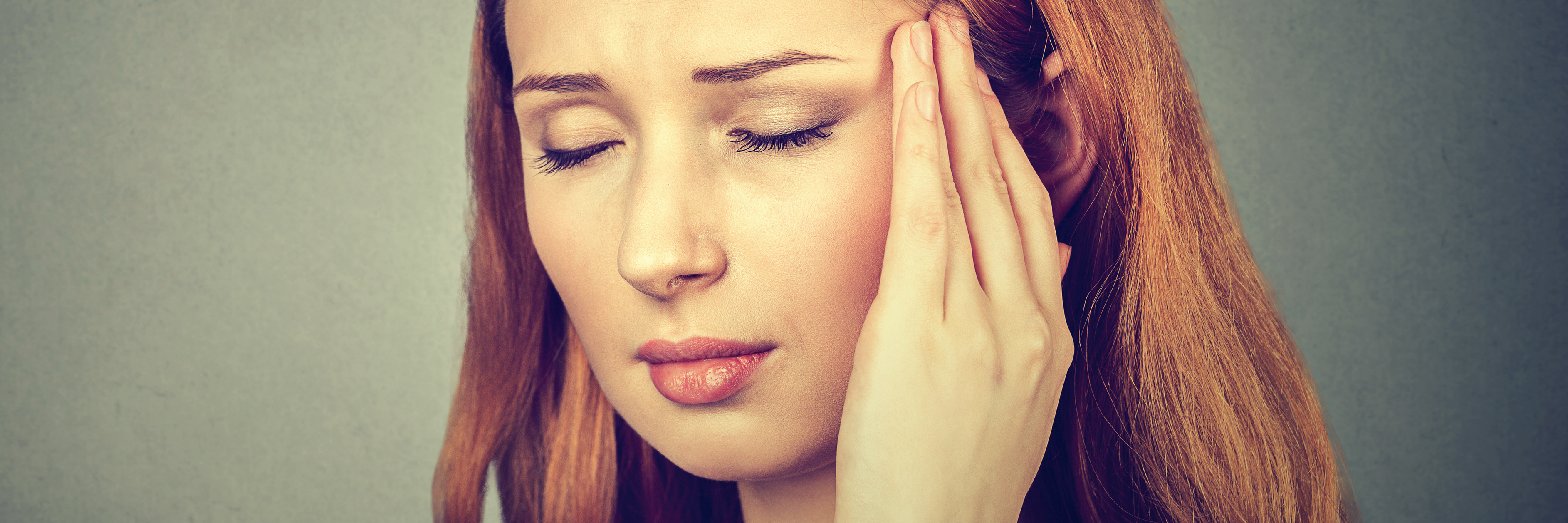 When You're Not Allowed to Struggle With Your Own Mental Health woman pressing fingers to temples isolated on gray wall background