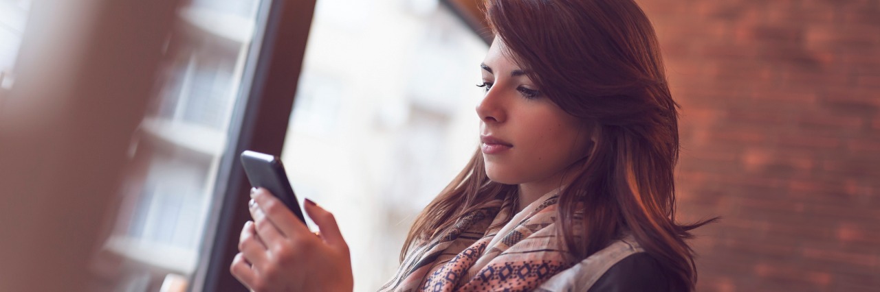 Social Media Posts Describing a Day With Ehlers-Danlos, Chronic Pain woman typing on her phone in a cafe