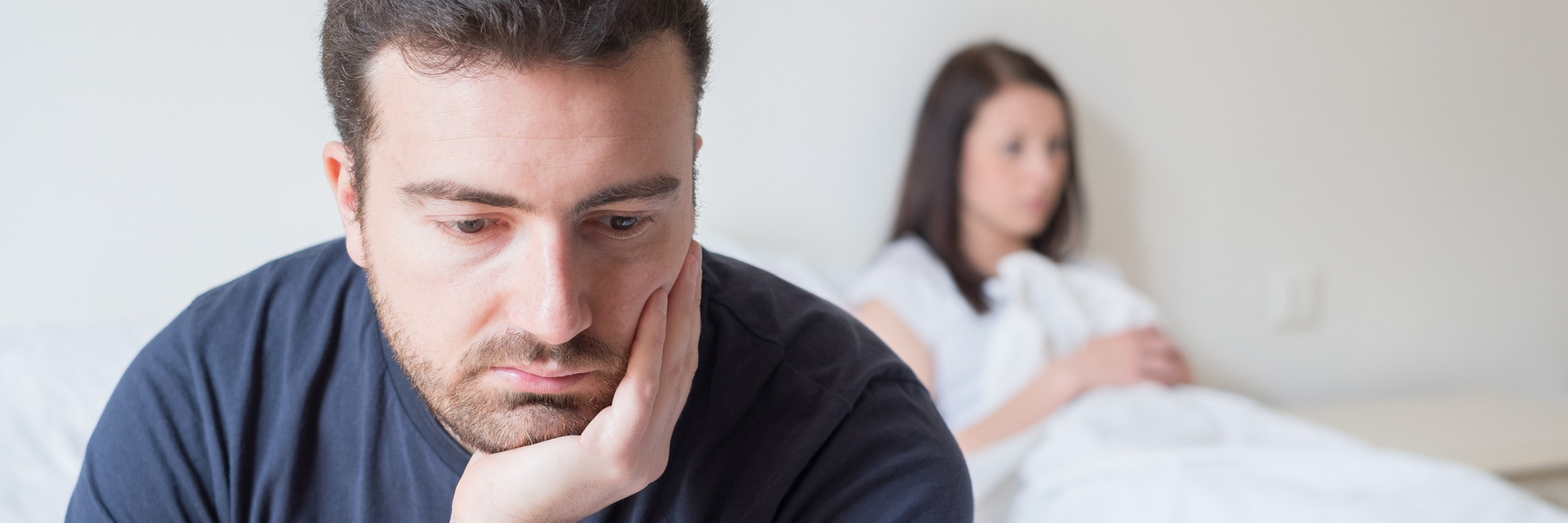 Your Wife Has Chronic Pain? Here's How You Can Support Her. A man sits, unknowing what to do as his wife is blurred in the background.