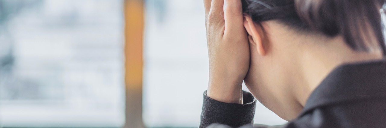 What It Means to Be Tired When You Have Anxiety Woman holding hand to head looking tired
