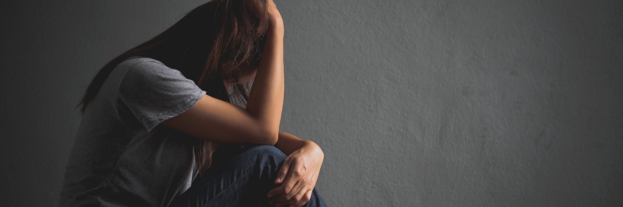 The Side of Hitting 'Rock Bottom' Nobody Likes to Talk About sad woman in empty room crying and hugging knees