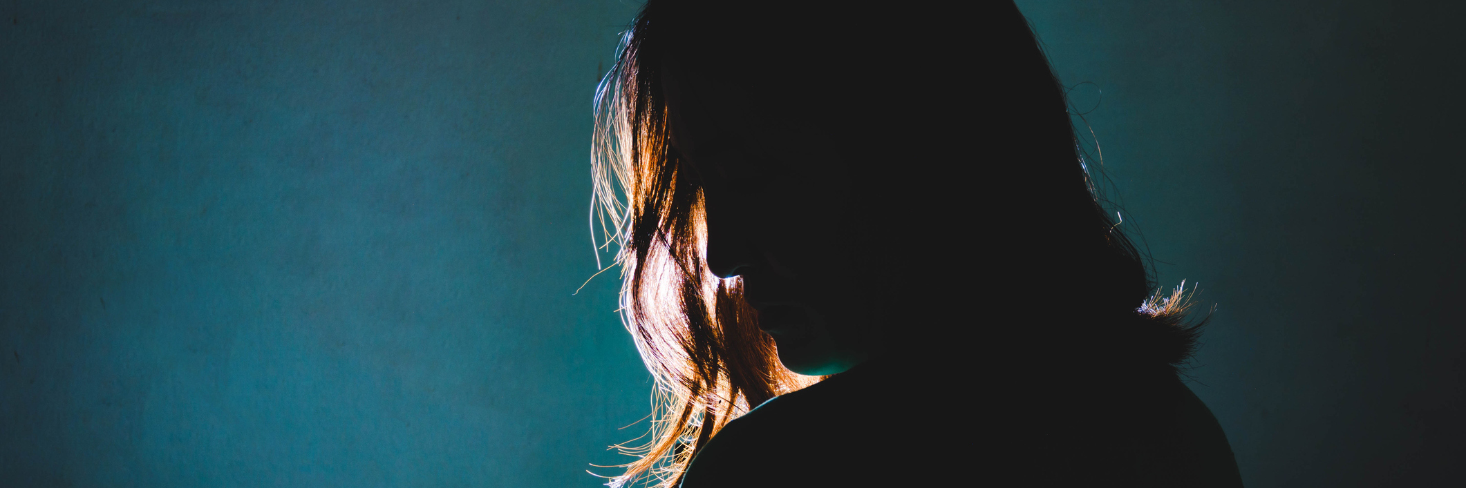silhouette of woman standing in the dark with light shine behind
