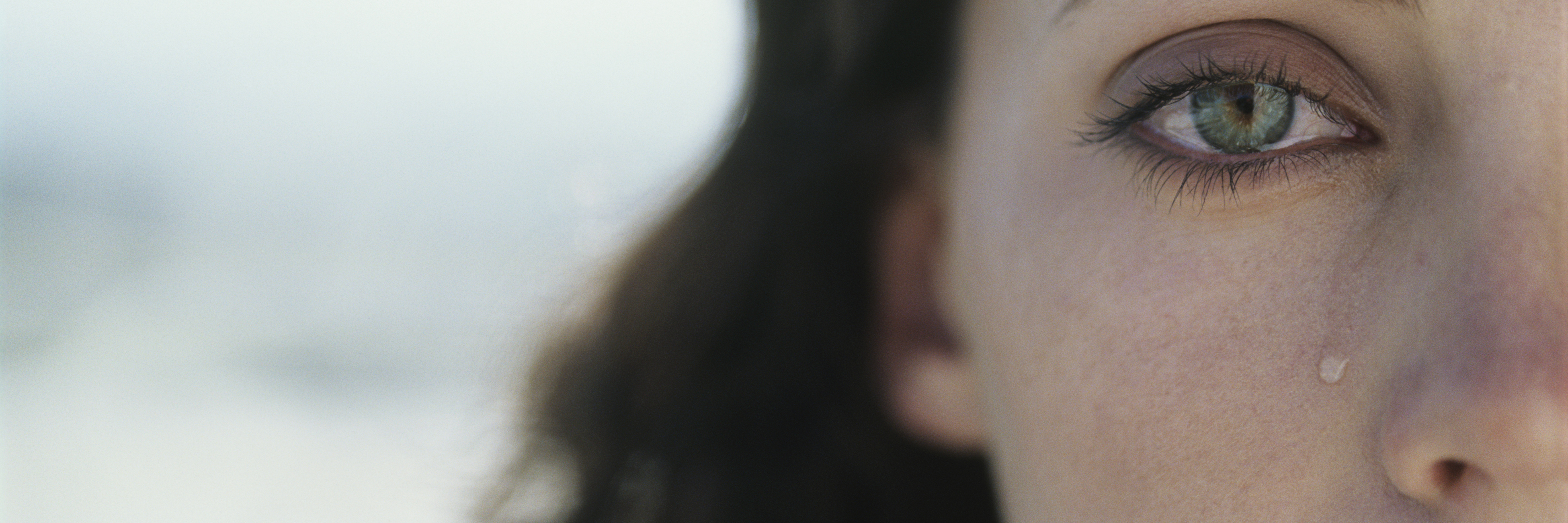 Why I Struggle to Believe My Mental Illness Makes Me Brave close up of young woman with brown hair crying with tear on cheek