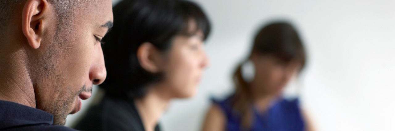 three people at a table, taking notes, during a meeting