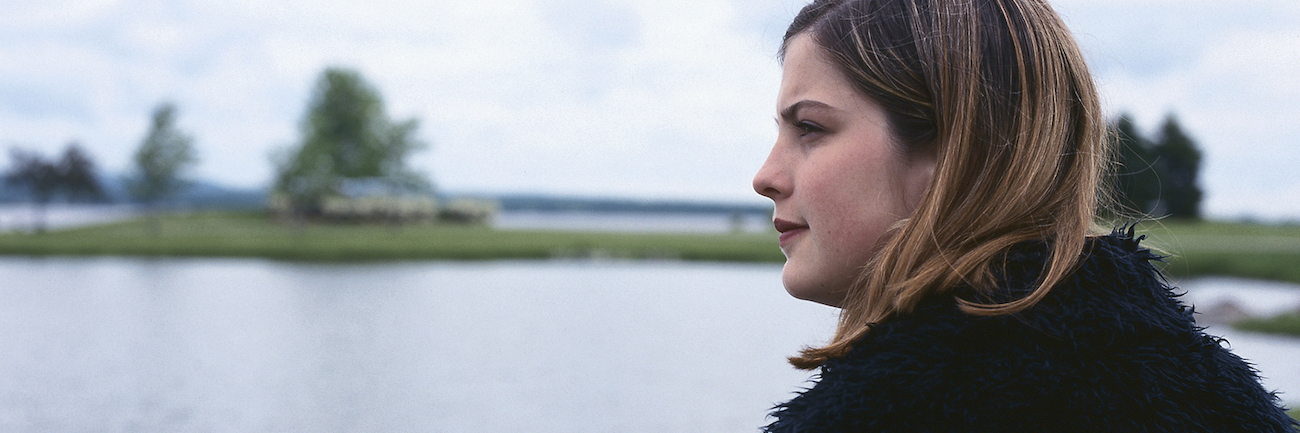 Woman sitting near lake, looking at landscape